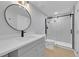Updated bathroom featuring a sleek vanity, modern round mirror, and a glass-enclosed shower at 6526 S Elmwood St, Littleton, CO 80120