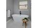 Bright bathroom featuring modern standalone tub, wooden side table, and gray tile flooring at 1735 Crestone Dr, Longmont, CO 80504