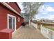 View of spacious backyard with a wooden deck, red house siding, and a white fence at 6202 Ralston St, Frederick, CO 80530