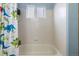 Clean white tiled bathroom features a shower and tub combination with a dinosaur-themed shower curtain at 6202 Ralston St, Frederick, CO 80530