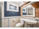 Well-lit bathroom showcasing a pedestal sink, toilet, and wood-framed mirror; window provides natural light at 7790 Kendall St, Arvada, CO 80003