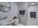 Bright bathroom featuring a modern sink, round mirror, and neutral color palette at 8745 W Ottawa Ave, Littleton, CO 80128