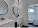 Bathroom featuring double vanity sinks with modern fixtures, round mirrors, and decorative plants at 8745 W Ottawa Ave, Littleton, CO 80128