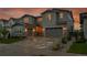 Beautiful two-story home with a long driveway and a well-maintained lawn, complemented by a striking sunset backdrop at 6912 Sunstrand Ct, Castle Pines, CO 80108