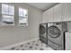 Bright laundry room featuring white cabinets, side by side washer and dryer, and decorative tile flooring at 6912 Sunstrand Ct, Castle Pines, CO 80108