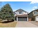 Charming two-story home featuring a large tree, gray garage door, and well-maintained front yard at 6393 Laguna Cir, Highlands Ranch, CO 80130