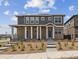 Charming two-story home with stone accents, covered porch, and landscaped front yard with blue sky at 18708 E 99Th Ave, Commerce City, CO 80022