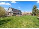 Spacious backyard with a green lawn and wooden deck featuring a covered lounge area, ideal for outdoor relaxation at 2153 Mountain Iris Dr, Erie, CO 80516