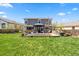 Large backyard featuring a well-manicured lawn, a wooden patio with outdoor lounge, and lush landscaping at 2153 Mountain Iris Dr, Erie, CO 80516