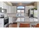 Modern kitchen features stainless steel appliances, white cabinets, granite countertops, and arched window with view at 2261 Alpine Dr, Erie, CO 80516