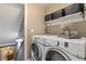 The laundry room has modern washer and dryer units with shelf space and storage baskets at 2261 Alpine Dr, Erie, CO 80516