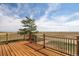 Spacious deck with wooden flooring and metal railings, overlooking a scenic landscape at 43343 E Arkansas Pl, Bennett, CO 80102