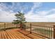 Wooden deck with metal railing and expansive views of open fields and picturesque skies at 43343 E Arkansas Pl, Bennett, CO 80102