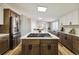 A bright kitchen features a large center island with a stovetop, counter seating, and modern white and brown cabinets at 43343 E Arkansas Pl, Bennett, CO 80102