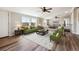 A bright living room with wood-look floors, large windows, and comfortable seating arrangements with green couches at 43343 E Arkansas Pl, Bennett, CO 80102