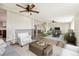 This open concept living room features wood flooring, and neutral tones with multiple seating areas and ceiling fans at 43343 E Arkansas Pl, Bennett, CO 80102