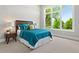 Bright bedroom featuring a large window, bed with decorative pillows, and wood nightstand at 1500 S Elizabeth St, Denver, CO 80210