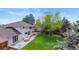 An aerial view shows a large backyard with patio, colorful furniture and surrounding mature trees at 5853 S Havana Ct, Englewood, CO 80111