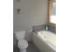 Bathroom with white tub, toilet, and window with natural lighting at 9274 Sandy Ln, Conifer, CO 80433