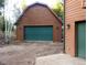 View of a detached garage with wood siding, a large green door, and exterior sconces at 9274 Sandy Ln, Conifer, CO 80433