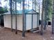 Metal shed with a green roof, double doors, and framed by mature trees at 9274 Sandy Ln, Conifer, CO 80433