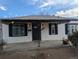 Close up of house facade highlighting the entry way, white siding, black shutters and a concrete porch at 6690 E 72 Pl, Commerce City, CO 80022