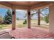 Inviting covered patio with stone tile flooring overlooking a lush green lawn and golf course at 7022 Secrest Ct, Arvada, CO 80007