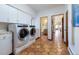 Bright laundry room with side-by-side washer and dryer, storage cabinets, and unique terra cotta-colored hexagonal tile floors at 7022 Secrest Ct, Arvada, CO 80007