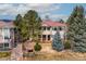 Lush rear exterior view of a home with a red tile roof, manicured landscaping and trees at 7022 Secrest Ct, Arvada, CO 80007