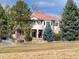 Rear exterior view of a house with an open backyard lawn surrounded by trees and landscaping at 7022 Secrest Ct, Arvada, CO 80007