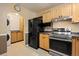 Kitchen featuring wood cabinets, black appliances, and an arched doorway to the living area at 3960 Cody St, Wheat Ridge, CO 80033