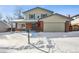 Two-story house with attached garage, visible in snowy landscape at 6663 Zinnia St, Arvada, CO 80004