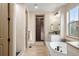 Bright bathroom features soaking tub, walk-in shower, and a view into the walk-in closet at 15252 W Warren Dr, Lakewood, CO 80228