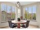 Bright dining room boasts large windows and a stylish light fixture over the wood table and leather chairs at 15252 W Warren Dr, Lakewood, CO 80228