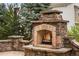 Outdoor stone fireplace with a burning fire, set amongst a well-maintained outdoor area at 15252 W Warren Dr, Lakewood, CO 80228