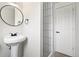 Modern bathroom featuring a pedestal sink, oval mirror, and tiled shower with black hardware at 206 Troy St, Aurora, CO 80011