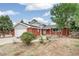 Charming red brick house featuring a well-manicured front yard and an attached garage at 206 Troy St, Aurora, CO 80011