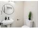 Modern powder room featuring a pedestal sink, round mirror and neutral wall colors at 206 Troy St, Aurora, CO 80011