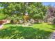 Manicured backyard with lush green lawn, mature shade trees, garden beds, and wooden fence offers privacy at 11412 W Roxbury Pl, Littleton, CO 80127