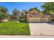 Inviting two-story home features a manicured lawn, mature trees, and an attached three-car garage at 11412 W Roxbury Pl, Littleton, CO 80127