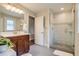 Bright bathroom with new shower, wood vanity, modern fixtures, and ceramic tile flooring at 4456 Yates St, Denver, CO 80212