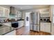 Bright kitchen featuring stainless steel refrigerator, white cabinets, and hardwood floors at 4456 Yates St, Denver, CO 80212