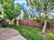 Well-maintained backyard featuring lush green grass, a wood fence, and mature trees at 11556 W Cooper Pl, Littleton, CO 80127