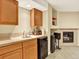 Basement bar area with wood cabinets, tile backsplash, small refrigerator, and adjacent fireplace at 11556 W Cooper Pl, Littleton, CO 80127