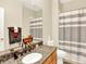 Cozy bathroom with granite vanity, matching cabinets, and shower/tub combination with gray-striped shower curtain at 11556 W Cooper Pl, Littleton, CO 80127