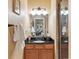 Well-lit bathroom featuring a wood vanity, granite countertop, large mirror, and walk-in shower with glass door at 8312 Hackamore Rd, Littleton, CO 80125