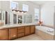 Bright bathroom featuring dual sinks, a soaking tub, and a glass-enclosed shower at 8312 Hackamore Rd, Littleton, CO 80125