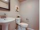 Bright bathroom features pedestal sink, white toilet, and sunflower wall art at 3540 E 5Th Ave, Denver, CO 80206