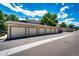 Row of garages with individual doors and assigned letters under a blue sky at 5439 S Dover St # 101, Littleton, CO 80123