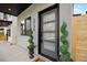 A close up of the front door with a modern design, green spiral topiary, and house numbers at 1735 Lowell Blvd, Denver, CO 80204